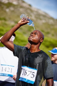 Shower after the run. a young male runner pouring water over himself after a road race.