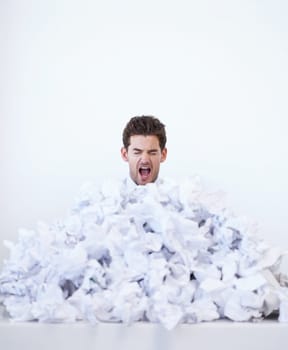 Argh This is too much. A young businessman looking frustrated while buried in a pile of papers.