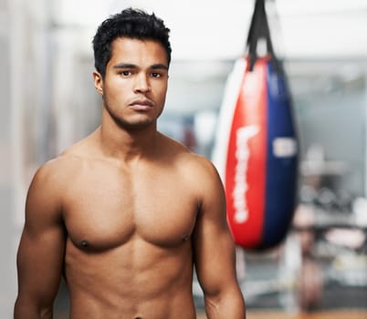 Boxing is his whole life. Portrait of a young boxer standing in a gym.