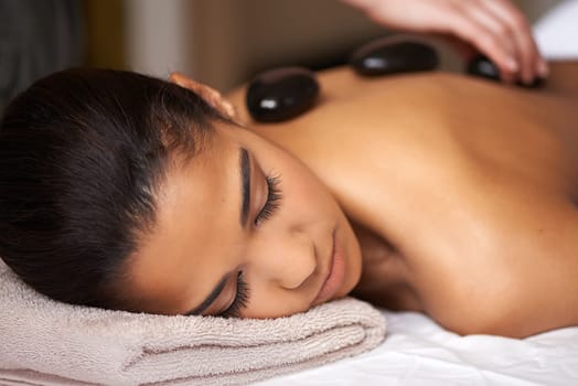 Woman, hands or back massage with rocks in spa to relax for zen, sleeping or wellness physical therapy. Girl, rest or calm client in salon to exfoliate for body healing treatment or hot stone therapy.