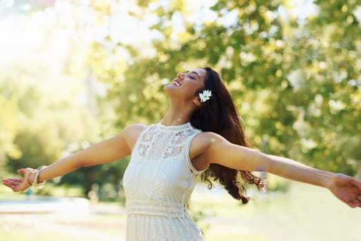 Free your spirit in the spring air. A young woman twirling in a park with her arms outstretched.
