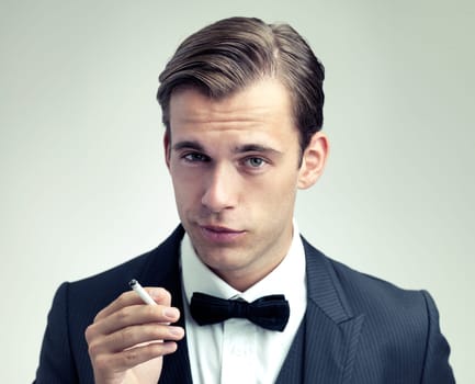 A man of sophistication. A cropped portrait of a confident young gentleman smoking a cigarette.