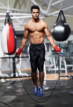 Boxing is his whole life. A handsome young boxer jumping rope in the gym.