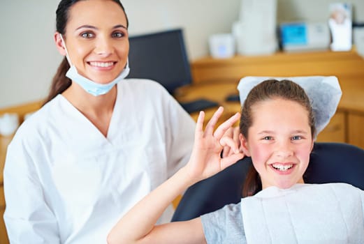 Another perfect checkup. Portrait of a young girl sitting in a dentists chair giving an ok sign.