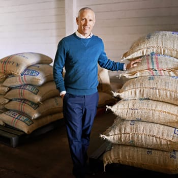 We only import the best and finest. Portrait of a mature man standing by bags on the floor of a warehouse.