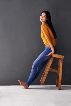 I lean towards the lighter side of life. Portrait of a happy young woman leaning sitting on a stool thats tilted back.