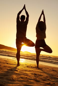 Position of happiness. Romantic shot of a couple practicing yoga on the beach