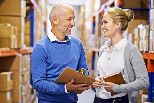 Coordinating shipping. a man and woman inspecting inventory in a large distribution warehouse.