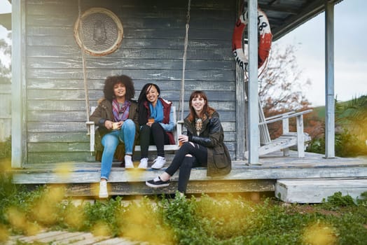 Our memories keep us together. a group of friends sitting on the porch of a fishing cabin together.