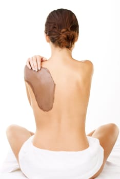 She has regular mud therapy. Studio shot of a young woman with a mud treatment on her back.
