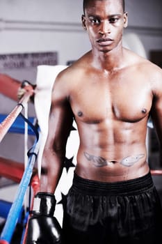 Nothing but success will do. A muscular young boxer standing ringside and looking at you.
