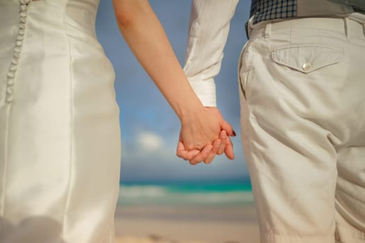 A man and a woman held hands against the backdrop of the sea close-up.