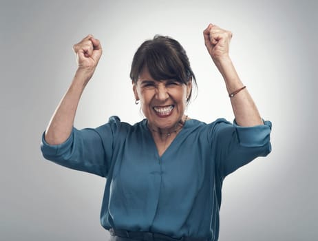 Heres my happy dance. Studio portrait of a senior woman cheering against a grey background.