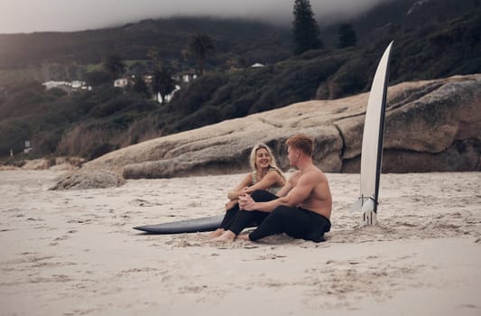We get to bond while waiting for the perfect wave. a couple out at the beach with their surfboards.