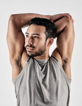 Sweat and sacrifice builds strength. Studio shot of a muscular young man stretching his arms against a white background.