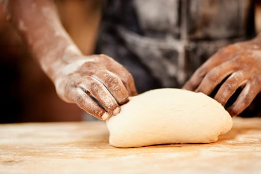 Meeting all your kneads. a male baker busy shaping dough at work.