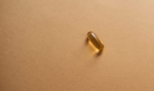 Supplement your vitamin intake with this. Studio shot of a single gel capsule against a brown background.