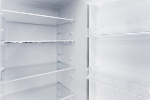 Empty white vertical new home refrigerator with shelves