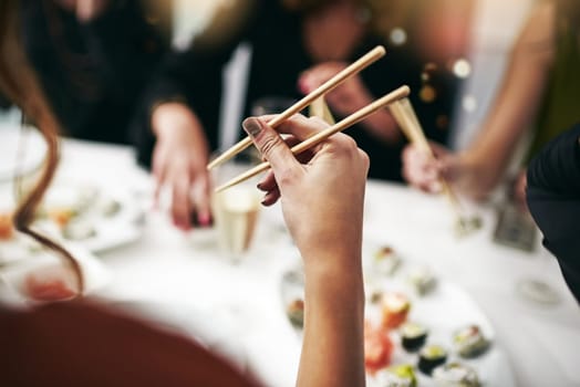 Chopstick, dinner party and woman hand at a restaurant at a table with drinks. Asian meal, sushi and friends celebration event with food and social group with drink together at a Japanese dining bar