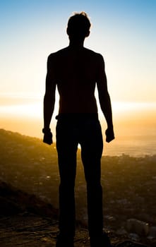 Man, silhouette and mountain in sunset for achievement, adventure or hiking journey in nature. Male hiker standing on cliff for trekking exercise view, accomplishment or motivation for fitness goals