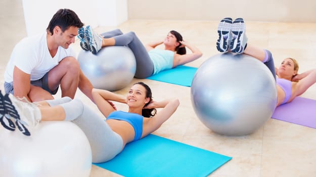 Personal trainer, pilates and ball for helping women with balance, posture and happy for training, fitness and gym. Man, exercise and help woman in class with stretching, wellness or workout on floor