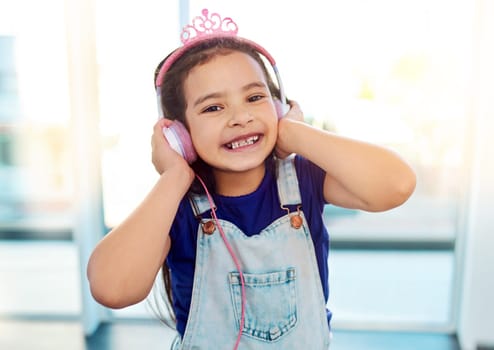 Music resonates through all ages and constructs. an adorable little girl listening to some music on her headphones at home.