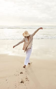 The sea has its own rejuvenating powers. Rearview shot of a young woman standing with her arms outstretched at the beach.