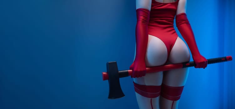 Sexy buttocks of a girl in a red bodysuit with an axe on a uniform blue background copypast