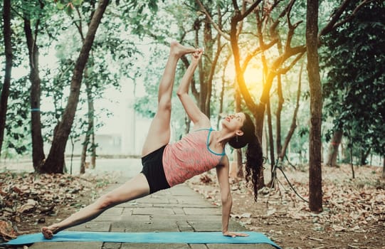 Beautiful girl practicing yoga power yoga at sunset. Young woman doing power yoga outdoors