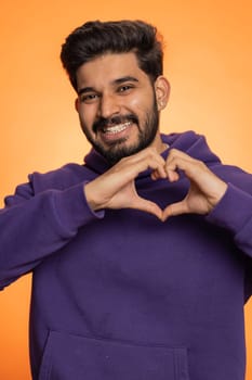 Smiling hindu man makes heart gesture demonstrates love sign expresses good feelings and sympathy