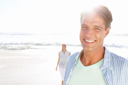Contentment is easy to see. A handsome mature man enjoying a walk on the beach with his wife.