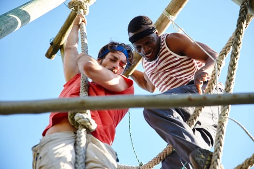 The difference between try and triumph is a little umph. two young men going through an obstacle course at bootcamp.