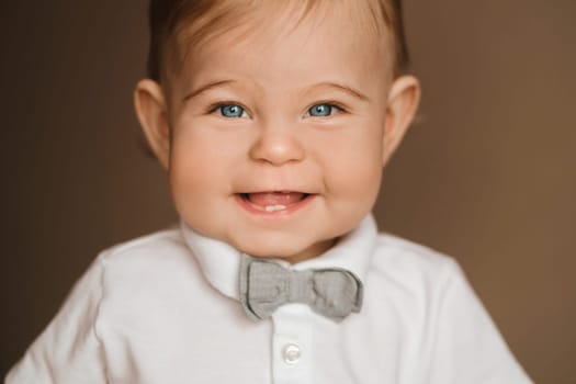 Portrait of a cheerful little boy in a white shirt with a bow tie
