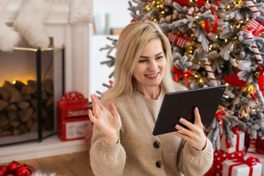 woman with tablet on the background of a Christmas tree.