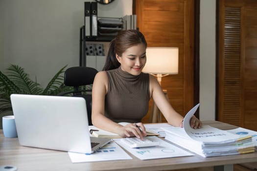 young woman calculating domestic expenses in financial paperwork indoors, focused lady managing monthly banking payments summarizing utility bills and taxes at home