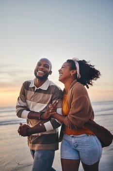 Happy couple, love and travel at the beach holding hands on date, quality time and romance at sunset. Black woman and man, laughing and walking together by the ocean on honeymoon during summer