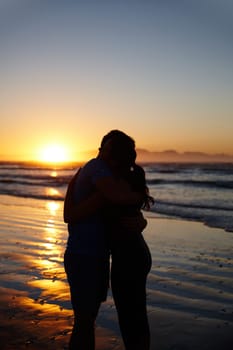 Romance at daybreak. Silhouette image of a couple hugging and kissing at sunrise.