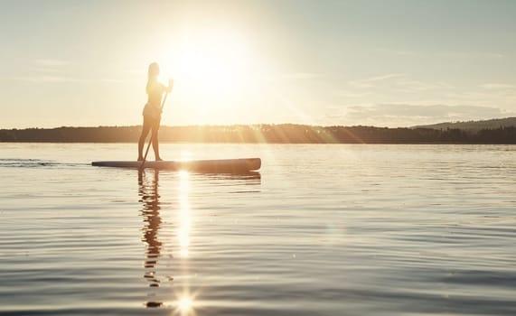 The calm of paddle boarding. an attractive young woman paddle boarding on a lake.