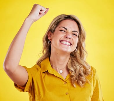 Woman, fist celebration and happy in studio for winning, goals and success for achievement by yellow background. Girl, excited and winner with bonus, profit and prize from competition by backdrop.