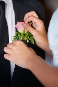 Its in the details. Closeup of a bride adjusting the pink rose on her husbands jacket.