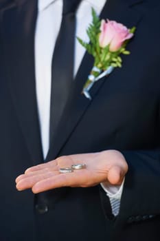 Giving the rings to his best man. Cropped closeup of a groom with the two wedding rings in the palm of his hand.
