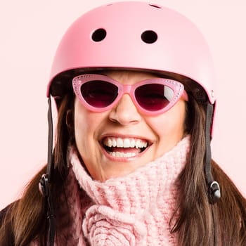 Staying young at heart. a mature woman standing alone in the studio while wearing sunglasses and a helmet.