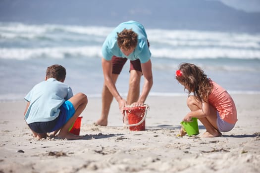 Enjoying the sun, sand and sea. a happy family building sandcastles together at the beach.