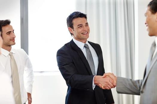Lets do some business. A positive businessman shaking hands with a coworker during a meeting.