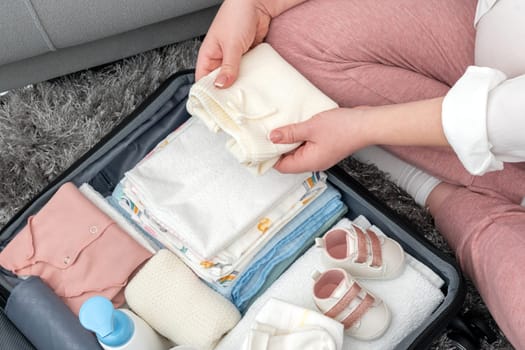 Pregnant woman packing suitcase for maternity hospital at home