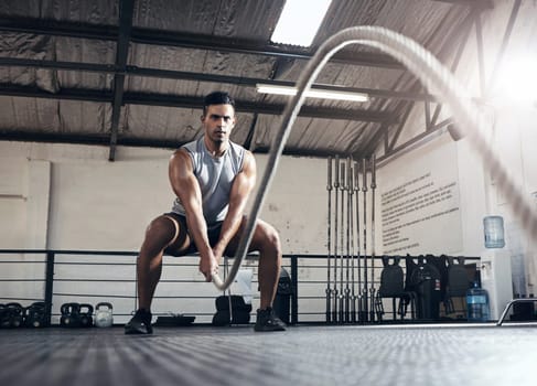 Rope, cardio and man training for fitness, body goal and health in the gym. Strong athlete with focus and energy doing exercise and workout for wellness, power and motivation at a sports club