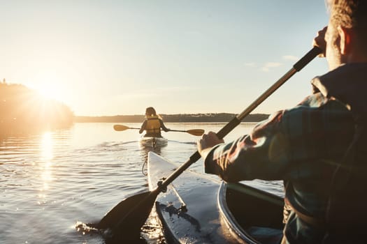 Kayak, lake and people rowing a boat on the water during summer for recreation or leisure at sunset. Nature, view and horizon with people canoeing for adventure, freedom or travel while on vacation