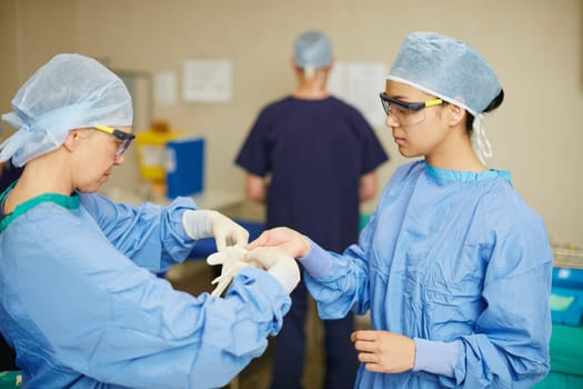 Making sure their operating room is germ free. surgeons putting on surgical gloves in preparation for a surgery.