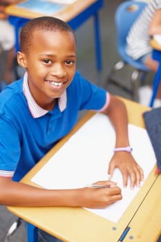 One of our brightest students, working hard as usual. Topview of a confident young african-american school pupil smiling up at you in class.