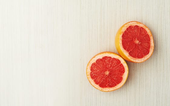 Juicy nutrients. Top view of a halved grapefruit lying on a light wooden surface.